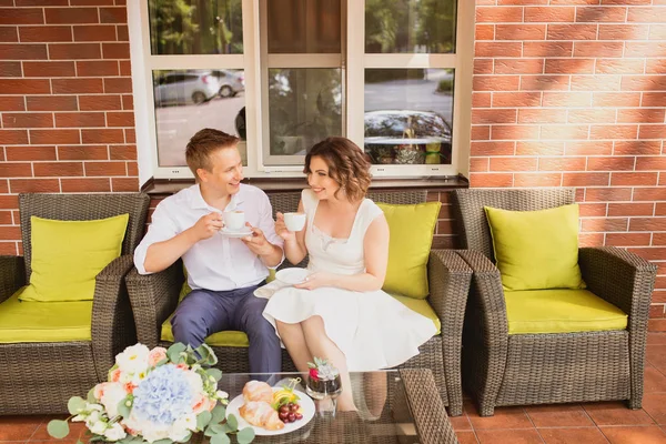 Çekici genç gelin ve damat kahve içip arka planda kafede oturuyorlar.