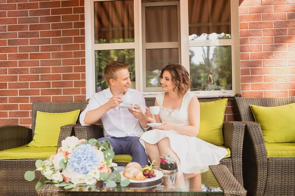 魅力的な若い花嫁と新郎がコーヒーを飲みながら屋外のカフェに座って — ストック写真