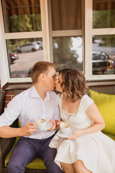 魅力的な若い花嫁と新郎がコーヒーを飲みながら屋外のカフェに座って — ストック写真