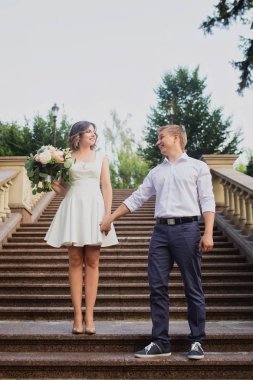 Genç gelin ve damat çimento mermer merdivenlerde poz veriyorlar.