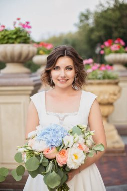 Bahçede çiçek buketi poz veren muhteşem genç köprü.