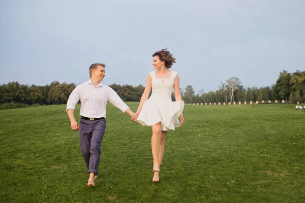 stock image beautiful young groom and bride walking on green park with lush green grass view background