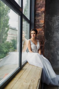 Gri bir arka planda güzel bir elbiseyle genç ve güzel bir gelinin portresi.