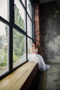 Gri bir arka planda güzel bir elbiseyle genç ve güzel bir gelinin portresi.