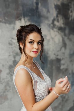 Gri bir arka planda güzel bir elbiseyle genç ve güzel bir gelinin portresi.