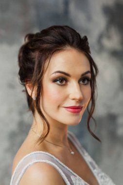 Gri bir arka planda güzel bir elbiseyle genç ve güzel bir gelinin portresi.