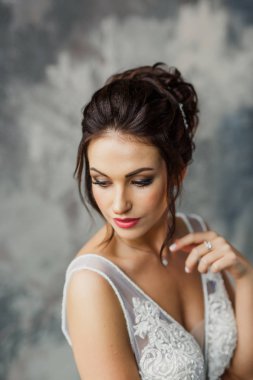 Gri bir arka planda güzel bir elbiseyle genç ve güzel bir gelinin portresi.