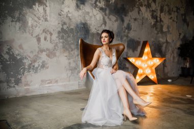 Gri bir arka planda güzel bir elbiseyle genç ve güzel bir gelinin portresi.