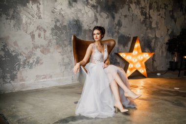 Gri bir arka planda güzel bir elbiseyle genç ve güzel bir gelinin portresi.