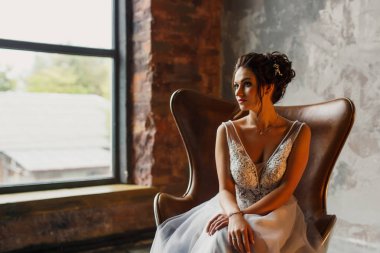 Gri bir arka planda güzel bir elbiseyle genç ve güzel bir gelinin portresi.