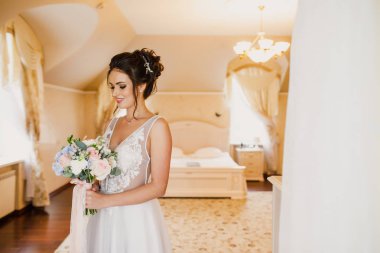 Gri bir arka planda güzel bir elbiseyle genç ve güzel bir gelinin portresi.