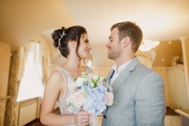 Genç ve güzel bir çift dairenin parlak bir odasında dikiliyorlar.