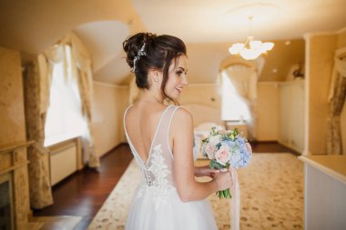 Gri bir arka planda güzel bir elbiseyle genç ve güzel bir gelinin portresi.