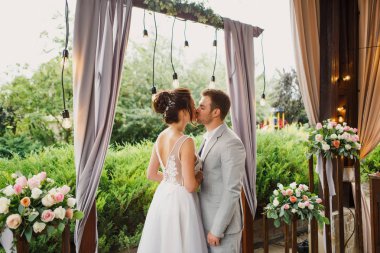 Güzel bir düğün çifti. Gelin ve damat düğün töreninde duruyorlar. Gelin çok güzel bir elbise giymiş. Damat çok şık giyinmiş.