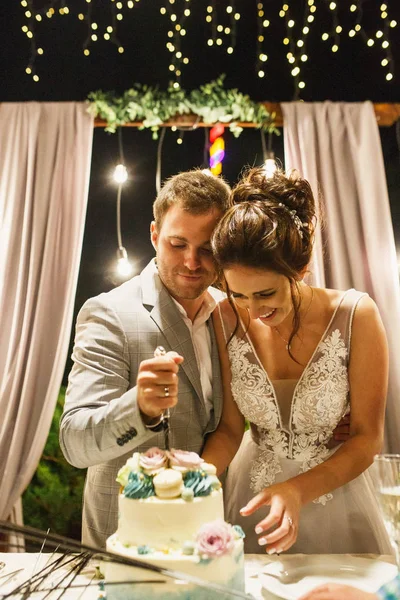 beautiful wedding couple the bride and groom cut the wedding cake at a wedding ceremony and have fun the bride in a beautiful dress the groom is dressed stylishly