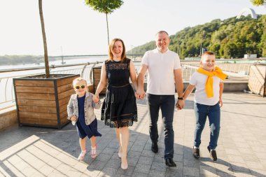 Genç aile babası anne ve kız gün batımında parkta yürüyorlar ve eğleniyorlar.