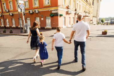 Genç aile babası anne ve kız gün batımında parkta yürüyorlar ve eğleniyorlar.