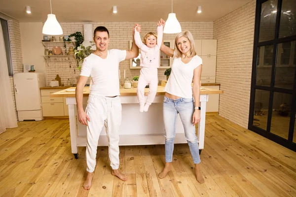 beautiful family dad mom and daughter have fun in the kitchen in a bright apartment