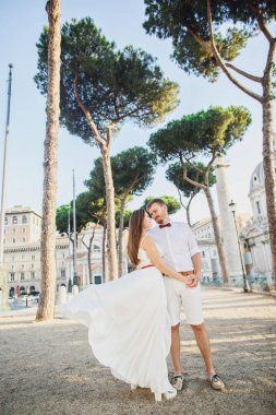 beyaz giysiler içinde genç güzel çift gün batımında İtalya'da Roma'da yürüyor