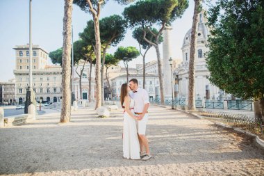 beyaz giysiler içinde genç güzel çift gün batımında İtalya'da Roma'da yürüyor