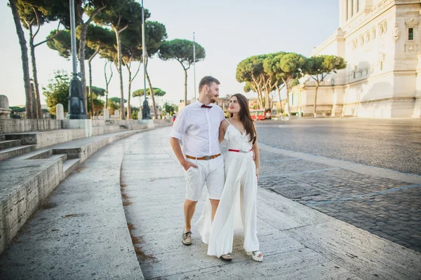 白い服を着た若い美しいカップルは 日没時にイタリアのローマを歩きます — ストック写真