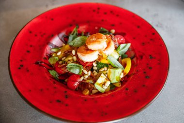 lezzetli ve iştah açıcı karides salatası, domates, ıspanak, peynir, fındık, pate bir restoranda kırmızı bir tabak üzerinde yatıyor