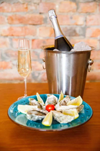 fresh and delicious oysters with lemon and a glass of champagne lie on a plate in a restaurant