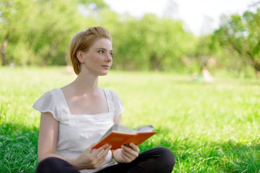 ciddi genç, güzel bir kız açık bir kitap okumak arka plan yaz yeşil park