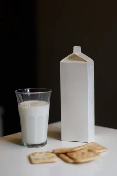 Kartonnen doos en glas melk op tafel in de keuken — Stockfoto