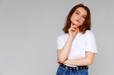 Hmm, güzel plan. Düşünceli, çekici ve komik genç Avrupalı kadın portresi. Tişörtünde dağınık bir çörekle çenesine el ele tutuşmuş. Sol üst köşeye bakıyor.