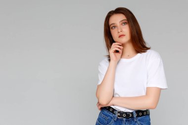 Hmm, güzel plan. Düşünceli, çekici ve komik genç Avrupalı kadın portresi. Tişörtünde dağınık bir çörekle çenesine el ele tutuşmuş. Sol üst köşeye bakıyor.