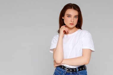 Hmm, güzel plan. Düşünceli, çekici ve komik genç Avrupalı kadın portresi. Tişörtünde dağınık bir çörekle çenesine el ele tutuşmuş. Sol üst köşeye bakıyor.