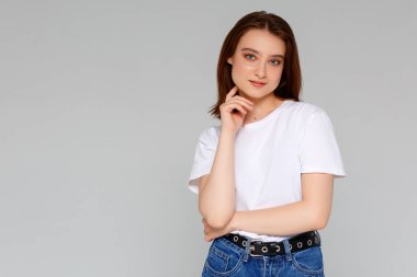 Hmm, güzel plan. Düşünceli, çekici ve komik genç Avrupalı kadın portresi. Tişörtünde dağınık bir çörekle çenesine el ele tutuşmuş. Sol üst köşeye bakıyor.