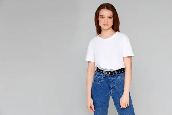 Beyaz tişörtlü, gri arka planda seksi bir kadın. Model.