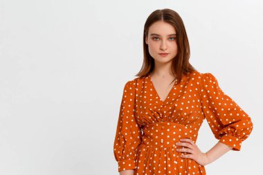 Güzel, gülümseyen genç bir kadın el ele tutuşup kameraya bakıyor. Monokromatik arka planda üç çeyrek uzunlukta stüdyo çekimi.