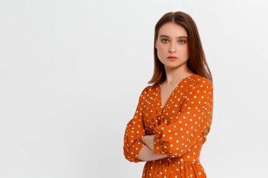 Çekici, kendine güvenen, yaratıcı, güzel görünümlü, patronluk taslayan, kollarını kavuşturan, kendine güvenen, gülümseyen, kendine güvenen, hedeflerine ulaşan, şanslı, tek renkli arka plan sahibi bir kadın.