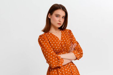 Çekici, kendine güvenen, yaratıcı, güzel görünümlü, patronluk taslayan, kollarını kavuşturan, kendine güvenen, gülümseyen, kendine güvenen, hedeflerine ulaşan, şanslı, tek renkli arka plan sahibi bir kadın.