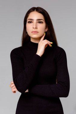 Gri arka planda siyah elbiseli güzel bir kadın.