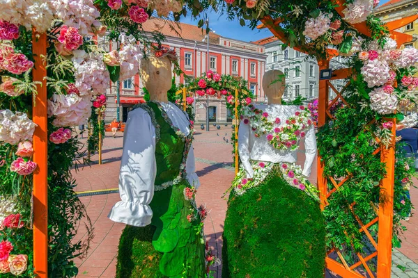 Decoração floral com duas estátuas de madeira vestidas com um c popular — Fotografia de Stock