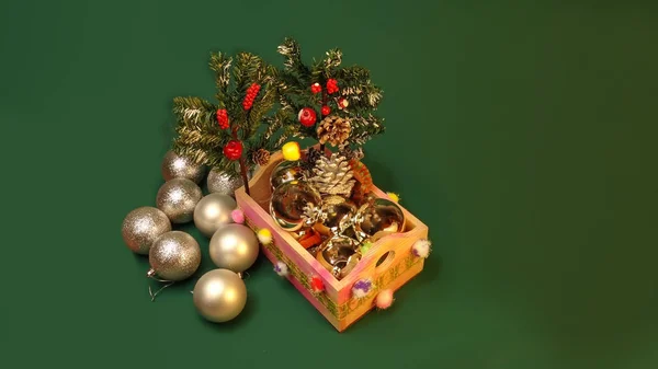 Šťastný Nový rok a Chritsmas. Stříbrné kuličky a kornouty v dřevěném koši se zelenými větvemi vánočních stromků. Domácí vánoční hračky a dekorace na zeleném pozadí. — Stock fotografie