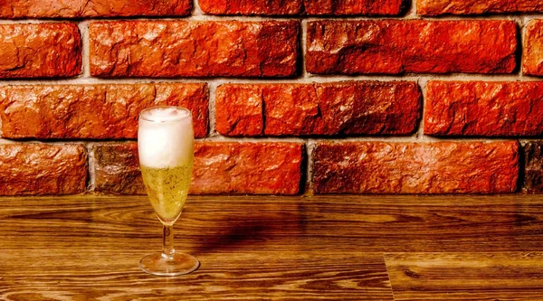Full glass off gouden champagne met schuim op rode baksteen achtergrond. Stockfoto