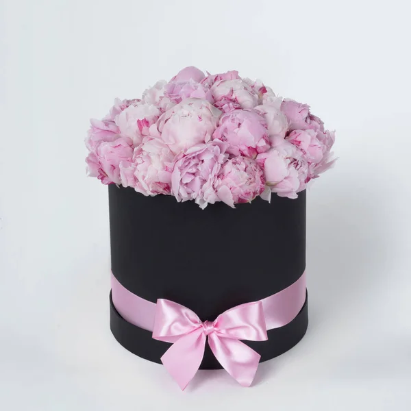 Luxury beautiful pink bouquet of peony flowers round black box with bow on gray background — Stock Photo, Image