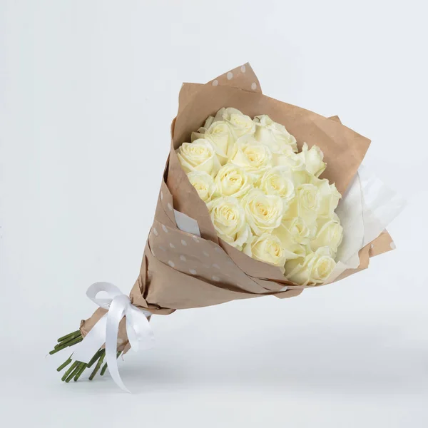 Bouquet of beautiful flowers of white roses in a kraft packing on a gray background — Stock Photo, Image