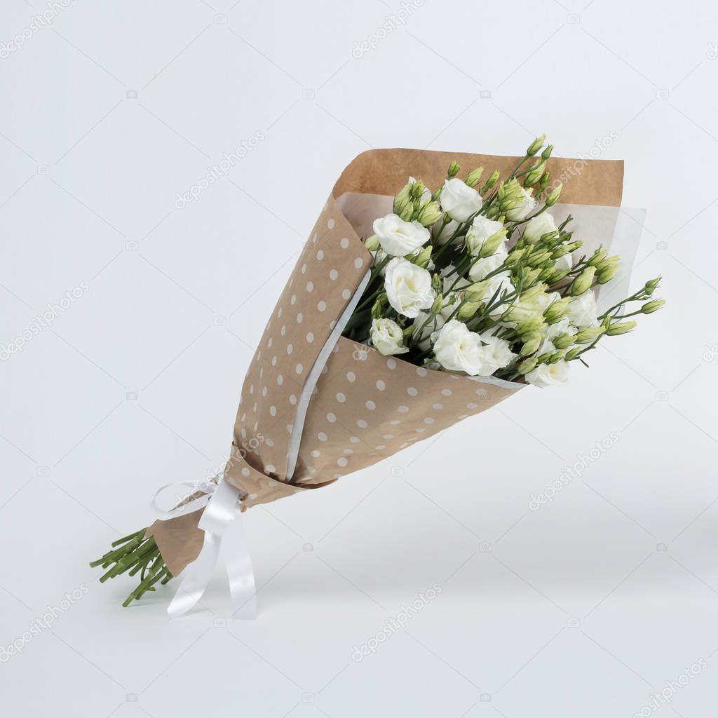 A bouquet of beautiful white flowers in a crafting package on a gray background