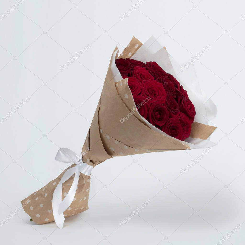 A bouquet of beautiful red roses in a kraft package on a gray background