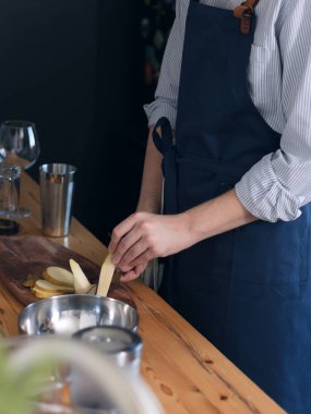 Mavi önlük mutfakta erkek barmen ahşap kesme tahtası üzerinde meyve kesme