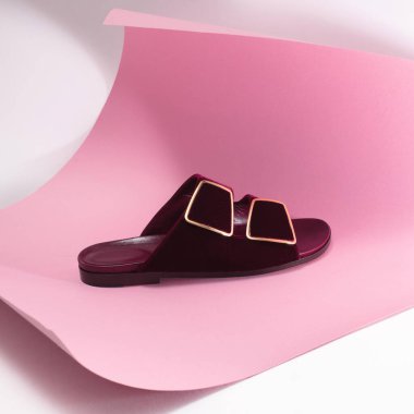 Pembe ve beyaz asfalt zemin üzerinde altın tokalı lüks süet bordo terlik, ayakkabı reklamı, pankart, maket