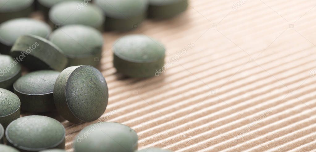 Detail of many organic spirulina tablets with low depth of field over cardboard background. 