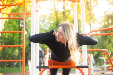 Yaz parkındaki kız arka tarafta spor egzersizleri yapıyor.