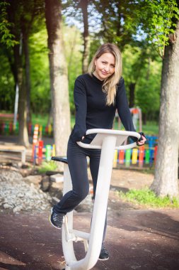 Yaz sporları sahasındaki kız egzersiz bisikletinde spor egzersizleri yapıyor. Sağlıklı yaşam tarzı.